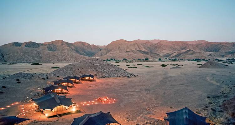 Zeltlager in der Abenddämmerung in Wüstenlandschaft.