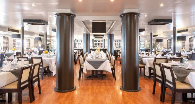 Speisebereich auf einem Kreuzfahrtschiff mit gedeckten Tischen.