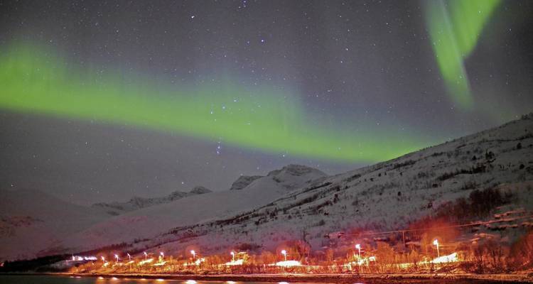 Aurores boréales au-dessus de montagnes enneigées la nuit.