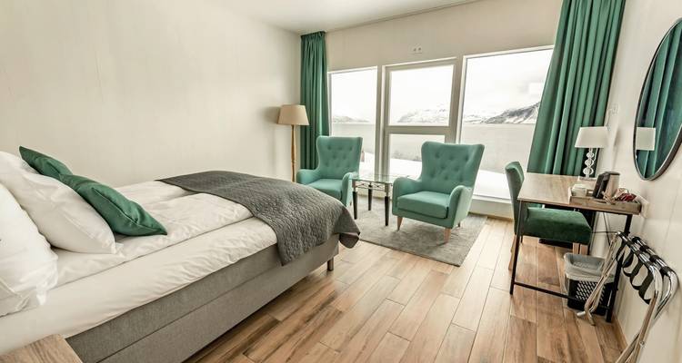 Chambre spacieuse avec vue sur les montagnes et un lac, dotée de fauteuils confortables.