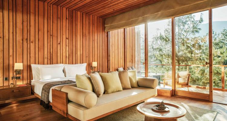 Luxuriöses Hotelzimmer mit Holzinterieur und großen Fenstern, die die Natur zur Schau stellen.