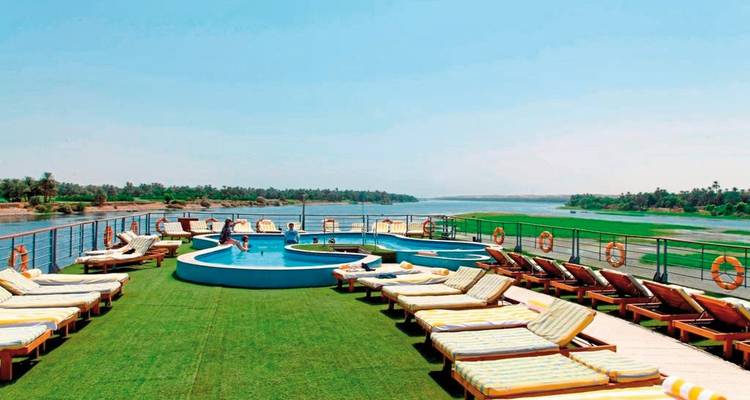 Cruiseschip dek met ligstoelen en kleine zwembaden met uitzicht op de rivier.