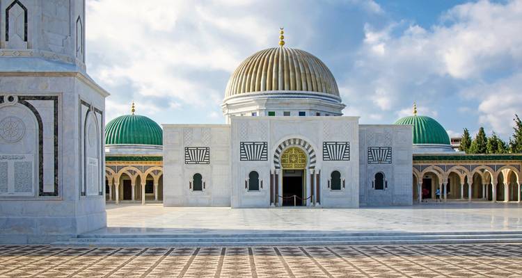 Majestic mosque with decorative domes and a clear blue sky.