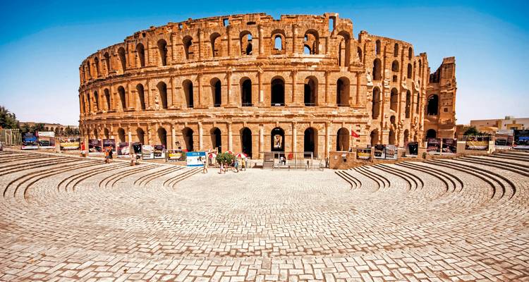 Grand amphithéâtre antique dans un cadre ensoleillé.
