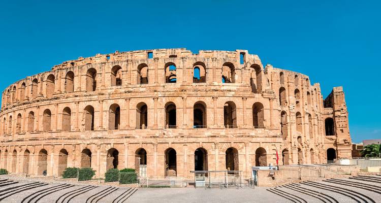 Ruines d'un amphithéâtre antique sous un ciel lumineux.