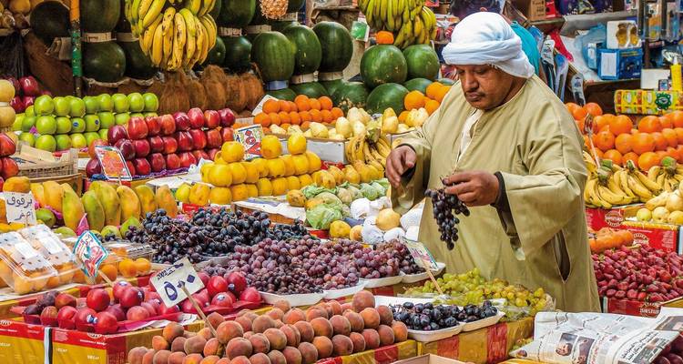 A market scene with a vendor arranging a colorful display of fresh fruits.