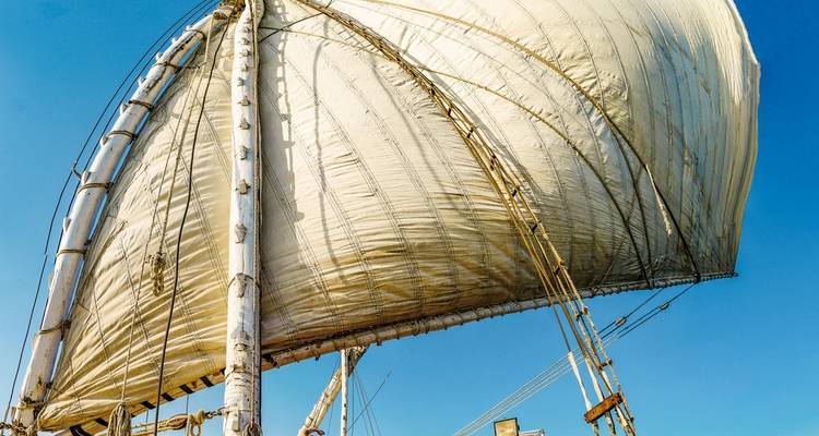 A traditional sail of an Egyptian felucca against a clear blue sky.