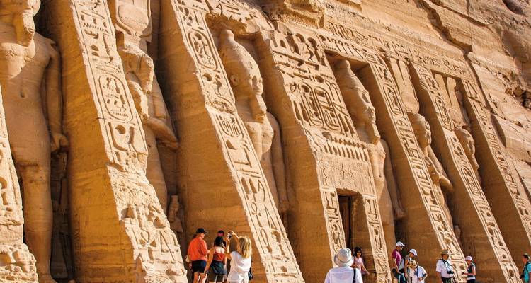 Tourists exploring the rock-carved temples of Abu Simbel with hieroglyphs.