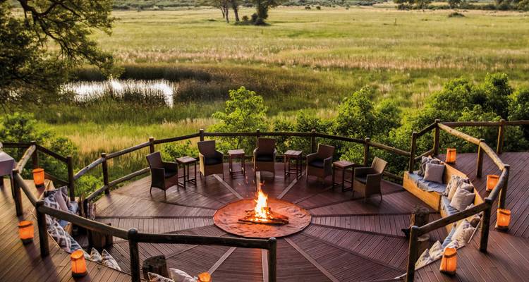 Fire pit surrounded by chairs overlooking a lush landscape.