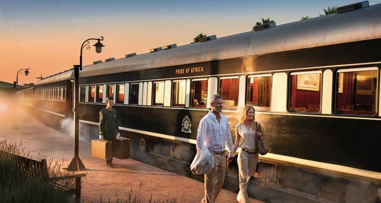 Des passagers embarquant dans le train Pride of Africa au coucher du soleil.