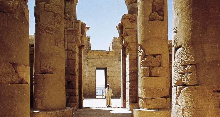 Oude Egyptische zuilen met een persoon die in ruïnes staat.