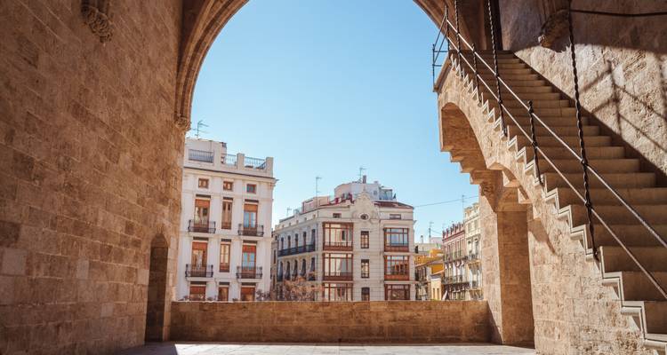 Zicht op historische gebouwen door een boog in Valencia.