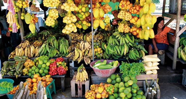 Vibrant fruit market stall with a smiling vendor.