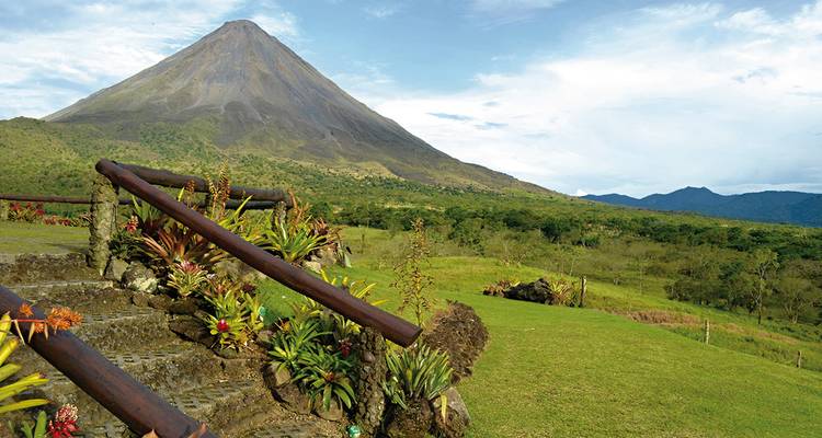 Uitzicht op de Arenal Vulkaan met weelderige voorgrond and blauwe lucht.