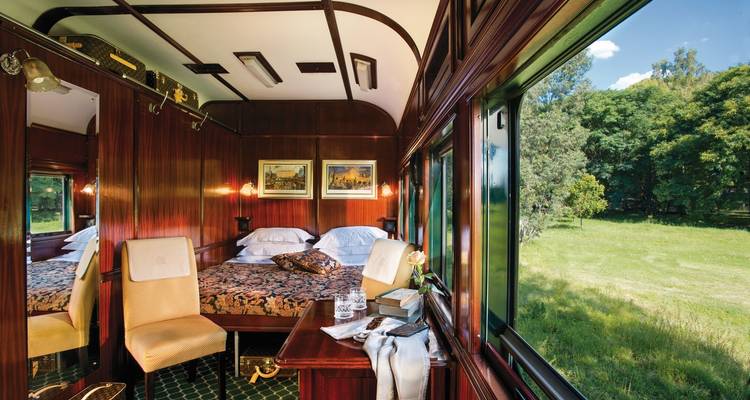 Luxurious train carriage interior with large windows and elegant decor.
