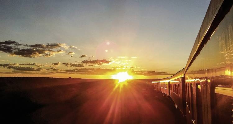 Train on railway tracks silhouetted against a sunset sky.