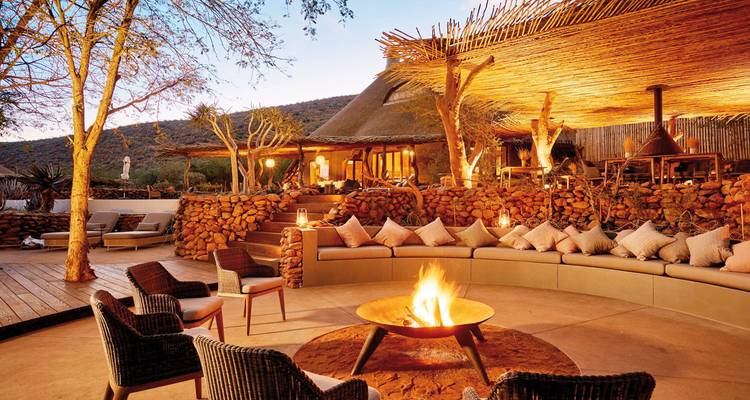Outdoor lounge area with a fire pit, surrounded by natural beauty at twilight.