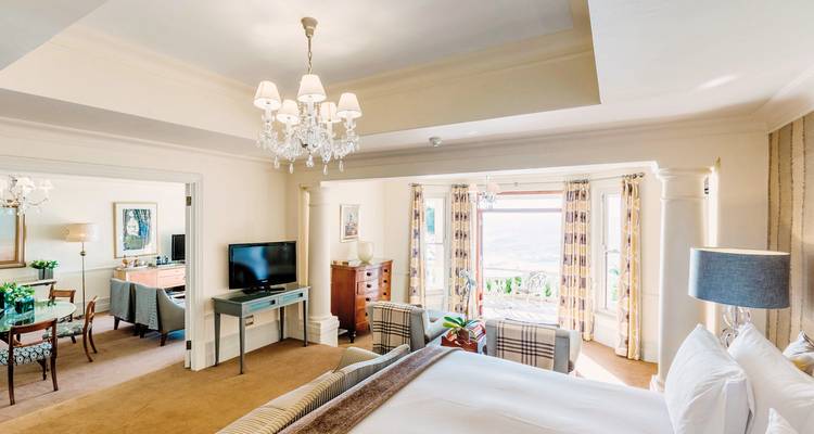 Spacious, elegant hotel room with a sitting area and view outside.