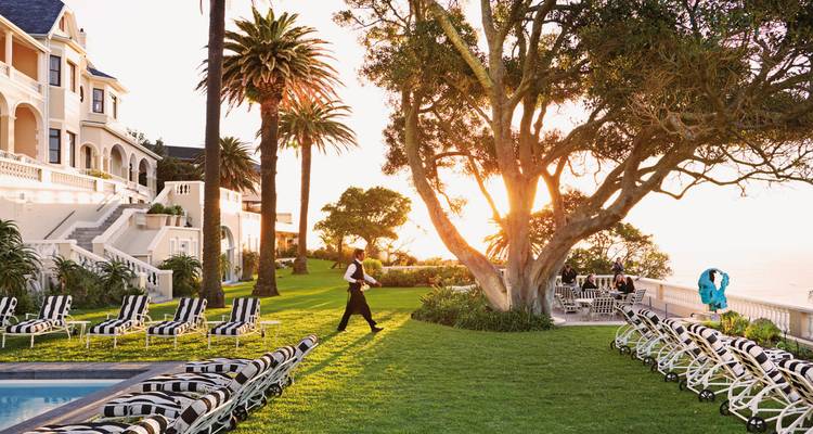Garden area of a hotel with pool, lounge chairs, and a waiter.