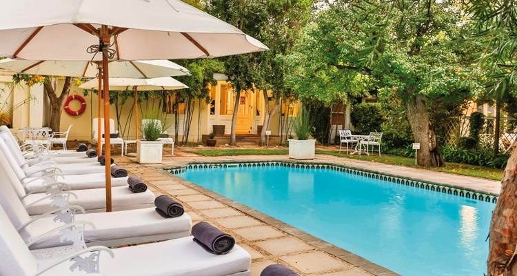Chaises longues et parasols de style vintage au bord d'une piscine.