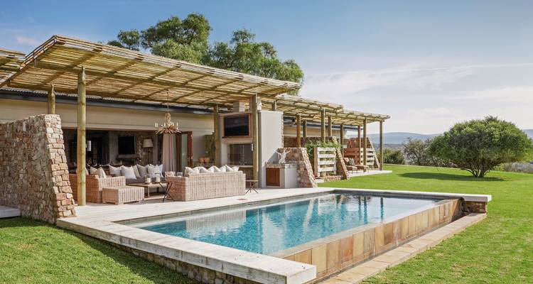 Une villa de luxe avec une piscine extérieure dans un jardin luxuriant.