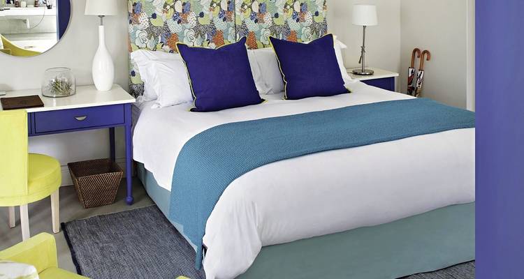 Chambre lumineuse et chaleureuse avec des accents bleus et une tête de lit à motifs.