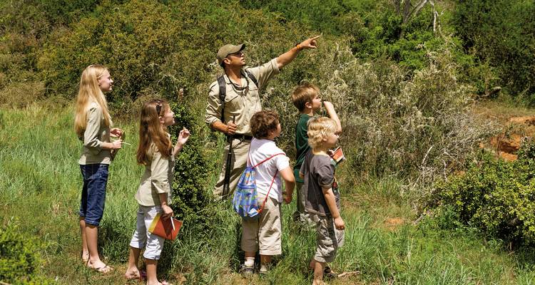 Groupe de personnes en promenade dans la nature avec un guide touristique dans une zone herbeuse.