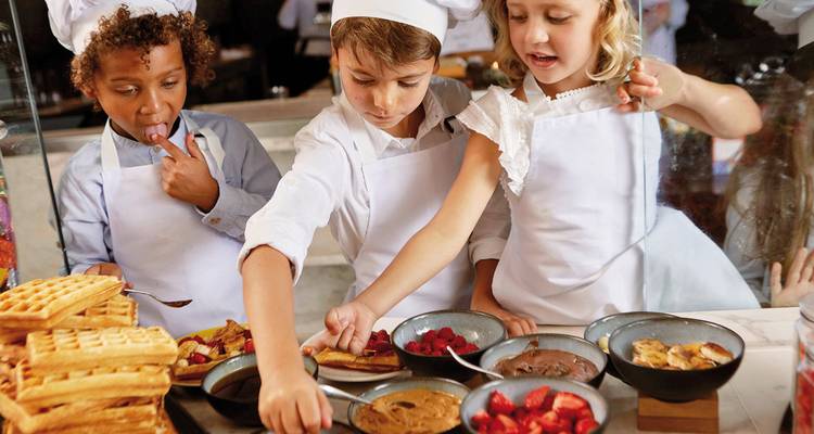 Enfants participant à une activité culinaire avec divers ingrédients.