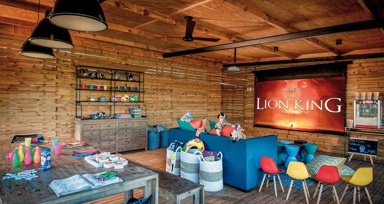 Salle de jeux intérieure avec thème du Roi Lion et jouets colorés.