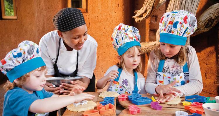 Kinder nehmen an einem Kochkurs mit einem Koch teil.
