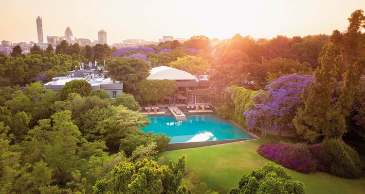 Weelderige tuin met een zwembadgedeelte and levendige bomen bij zonsondergang.