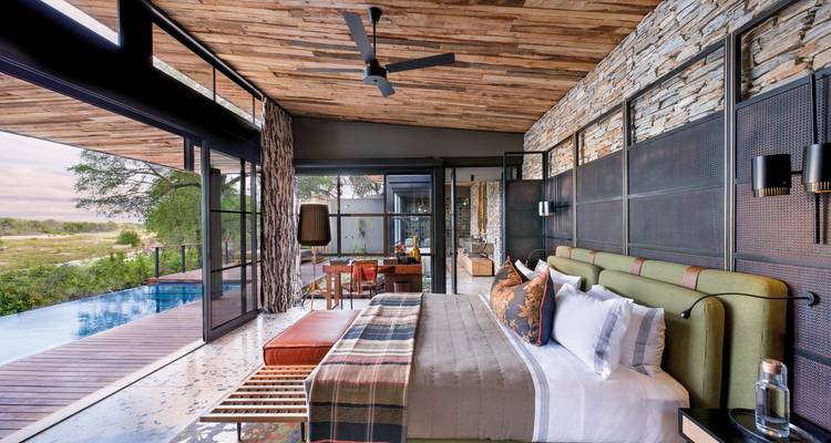 Posh interior of a lodge suite overlooking a river with a pool.