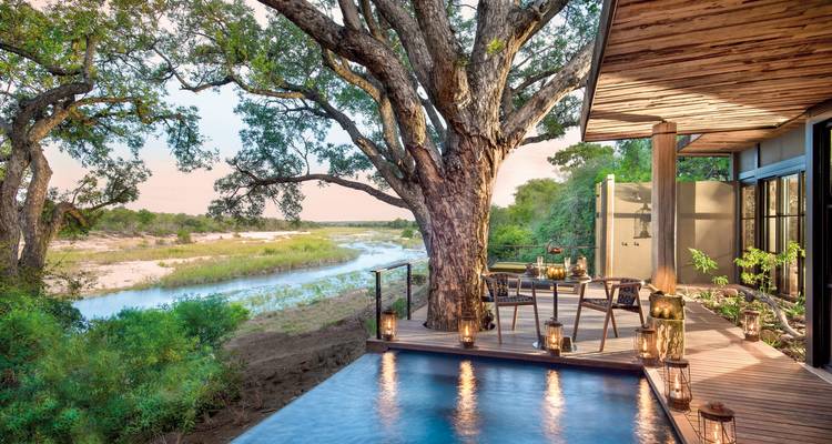 Outdoor deck with a plunge pool overlooking a river and trees.