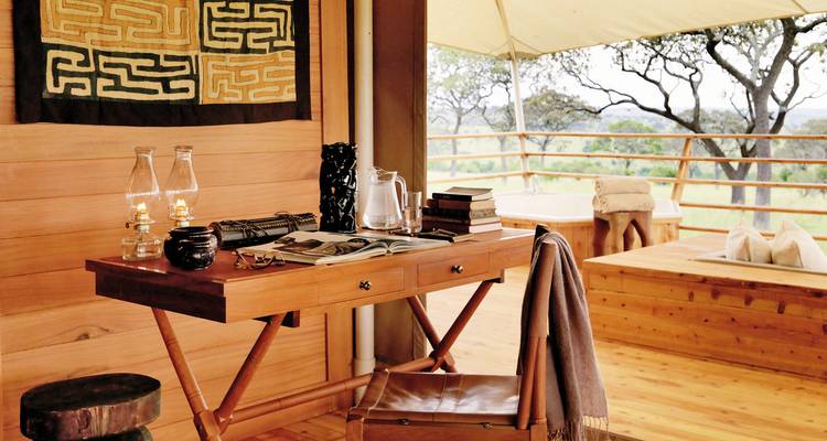 Innenraum einer Safari-Lodge mit Schreibtisch und Aussicht.