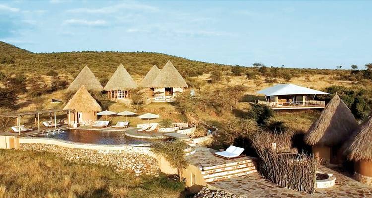 Reetdachlodges mit Pool umgeben von afrikanischer Savannenlandschaft.