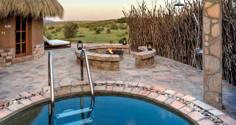 Außenbereich mit kleinem Pool und Feuerstelle, mit Blick auf die Savanne.