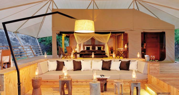 Innenansicht eines Luxuszeltes mit Sitzbereich und Bett.