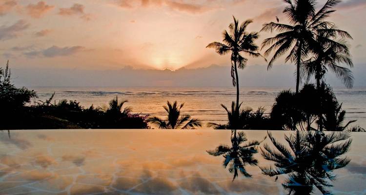 Schilderachtig zonsondergangzicht over een zwembad met palmbomen.