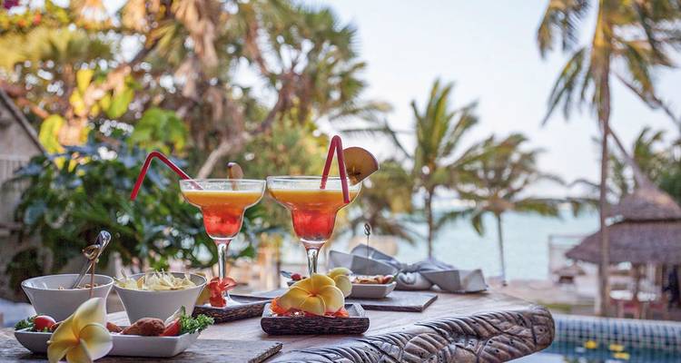 Kleurrijke cocktails en eten bij een zwembad aan het strand.