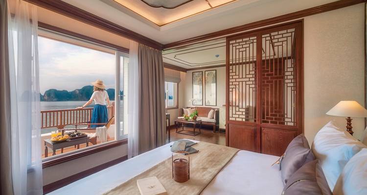 Interior of a luxury cabin with a view of water and a woman standing by the railing.