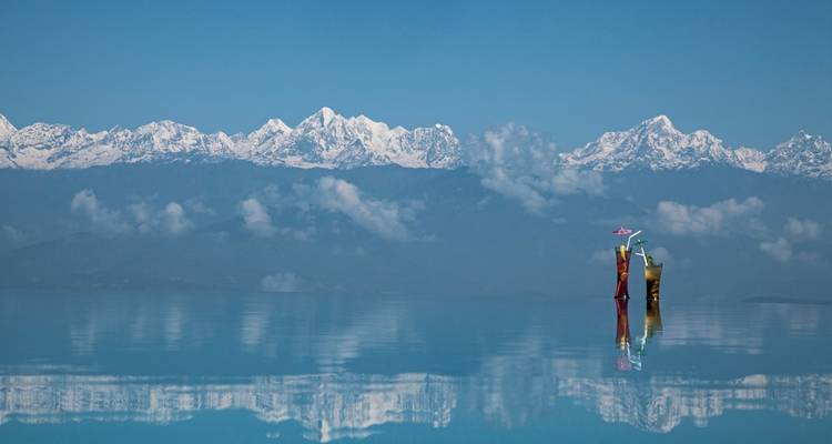 Ein Blick aus großer Höhe auf schneebedeckte Berggipfel mit einer ruhigen Wasserspiegelung.