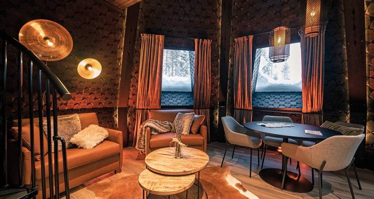 Innenraum einer Holzhütte mit modernen Möbeln und großen Fenstern.