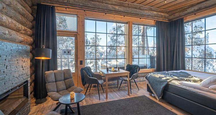 Gemütliche Luxus-Blockhütten-Suite mit großen Panoramafenstern mit Blick auf verschneiten Wald