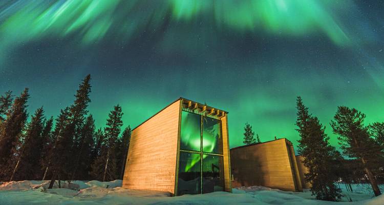 Moderne Glaskabinen unter lebendigen grünen Nordlichtern und sternenklarem Himmel