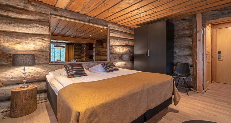 Rustikales Schlafzimmer mit Blockwänden, erdigen Tönen und großem Spiegel, der das Kabineninnere widerspiegelt