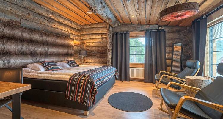 Geräumiges Schlafzimmer in einer Holzhütte mit gestreiften Akzenten und bequemen Stühlen am Fenster