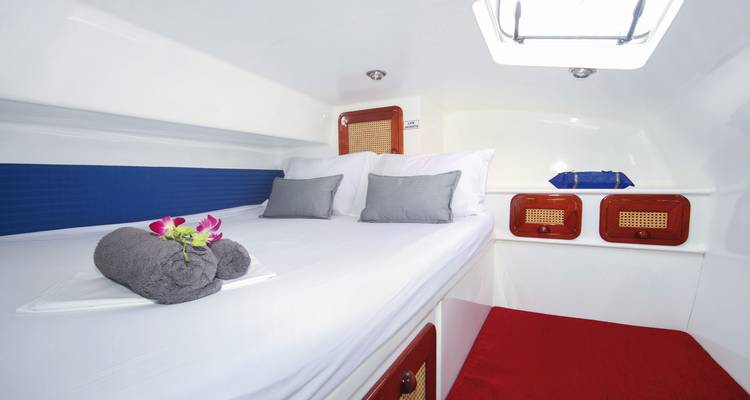 Interieur hut van een boot met een bed en handdoeken.