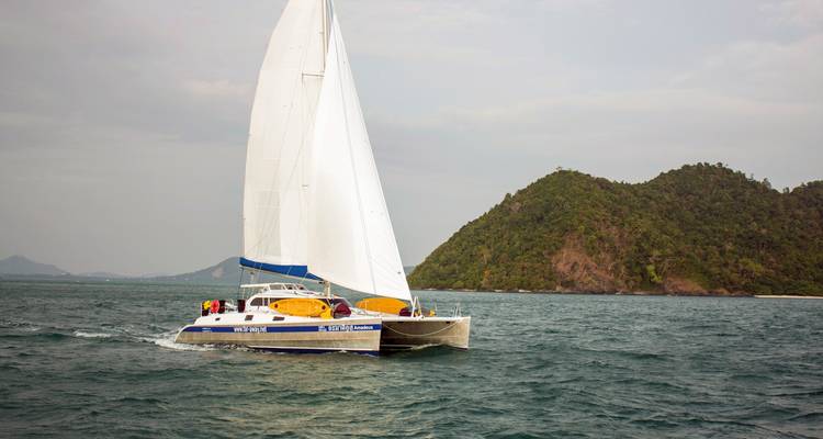 Zeilboot in open water met een eiland op de achtergrond.