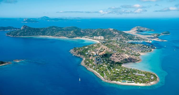 Aerial view of an island with surrounding waters and distant islands.