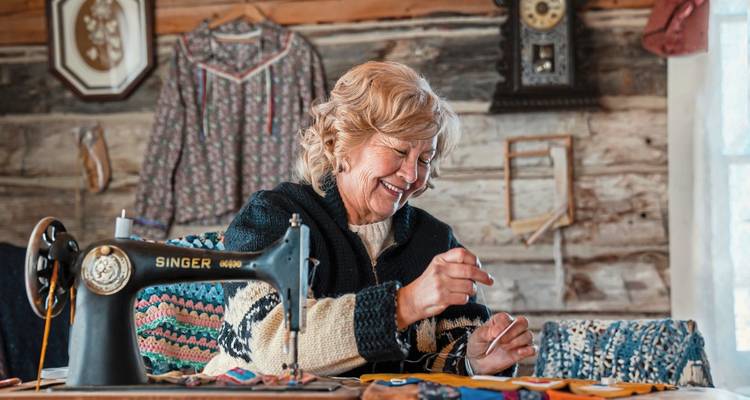 Woman sewing in a cozy wooden room.